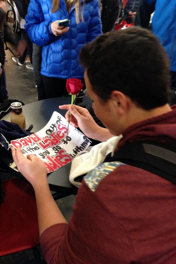 Sophomore David Mondry reads a sign inviting him to the dance. “David, out of all the ladies, I want you to come with me to Sadie’s.”
