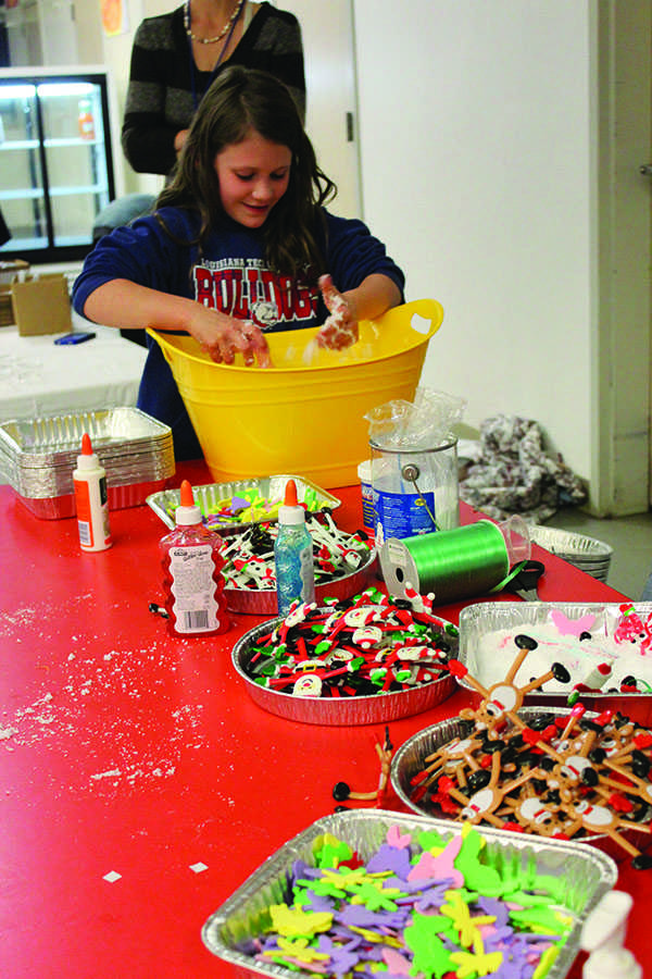 One of the student at the Holiday Festival plays with synthetic snow at the diorama making station.