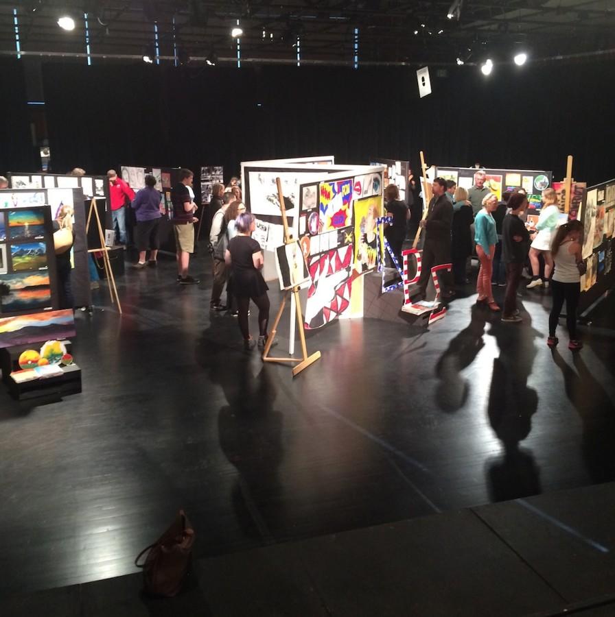 Students, teachers, family and community members roam around the Black Box Theatre on opening night of the annual IB Art Show 
