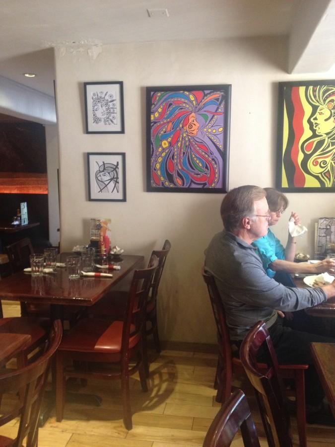 Customers enjoy their food while sitting next to the abstract art featured on the wall. 