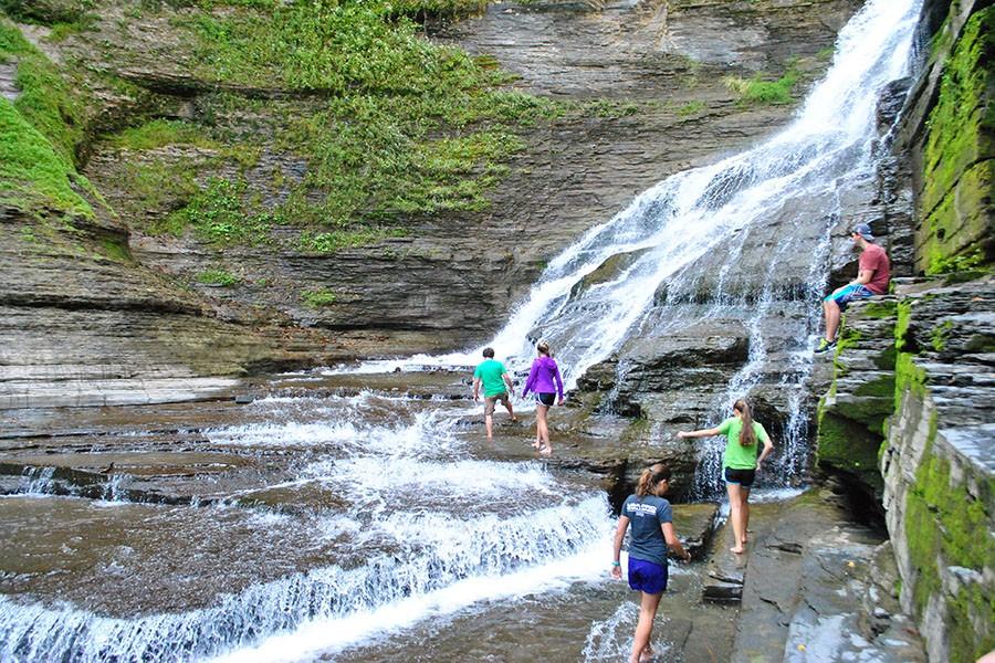 Students on Forging the Finger Lakes Ex Ed in 2014 climb a waterfall in Watkin’s Glenn, New York. 