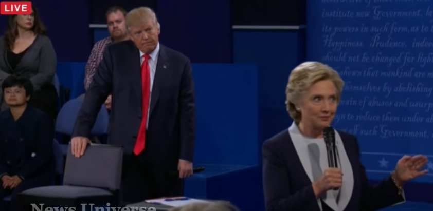 Trump scowls as he pauses from his pacing behind Clinton as she directly addresses an audience member.