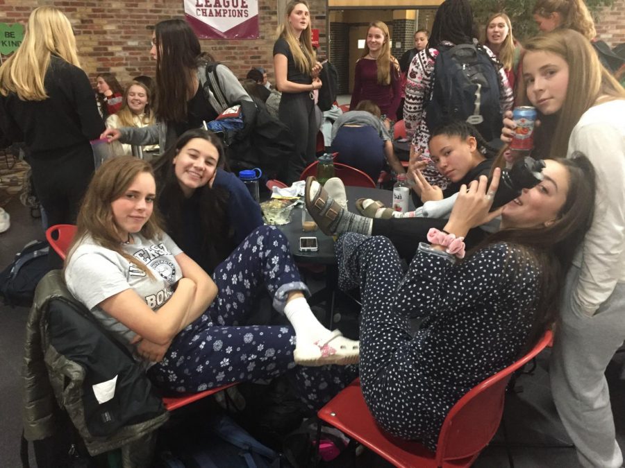 A group of students enjoy PJ day in the commons while homecoming proposals continue in the background.