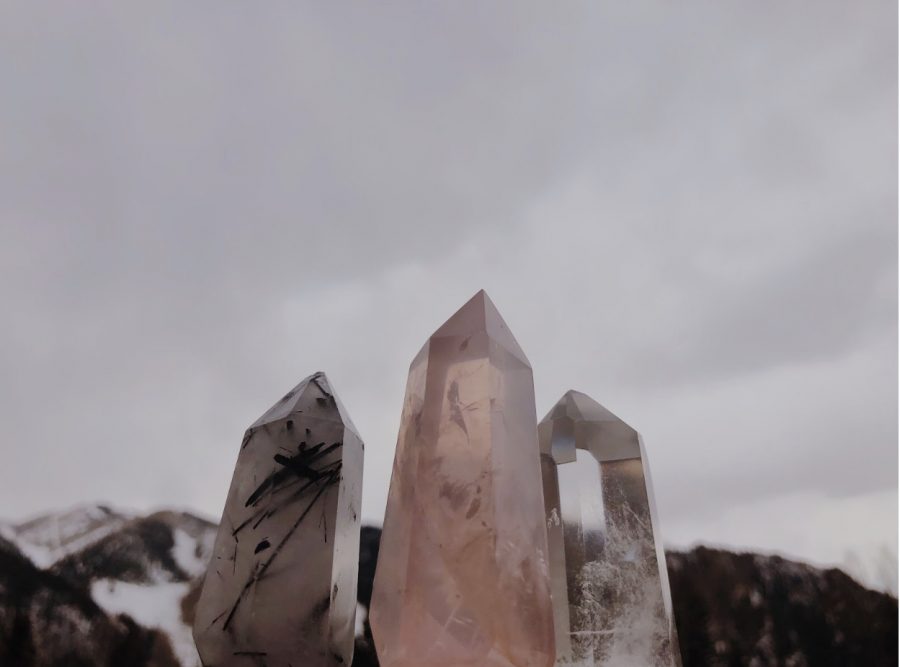 Three dazzling crystal points on a cloudy day with snowy Aspen mountain in backround from left to right: Black Tourmaline Crystal Quartz, Rose Quartz, Crystal Quartz.