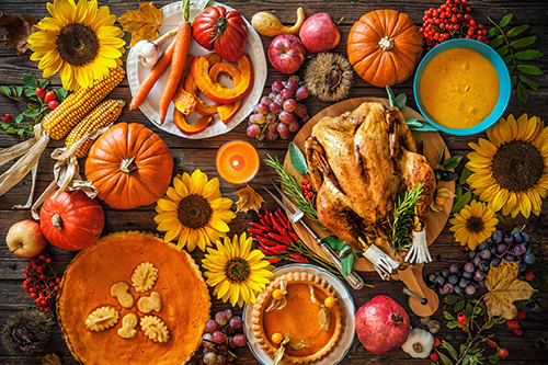 Thanksgiving dinner. Roasted turkey with pumpkins and sunflowers on wooden table. 