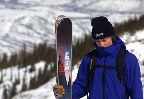 Sam Gibb Standing on a mountain with his skis in hand.