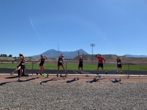 Runners (from left) Edie Sherlock, Stella Sherlock, Kylie Kenny, Michaela Kenny, Coach Chris Keleher, and Macy Hopkinson jump for joy after their Hotchkiss race.