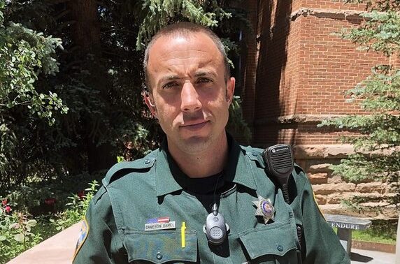 Cam Daniel, Aspen High Schools new School Resource officer, posing for a photo outside of the AHS building.