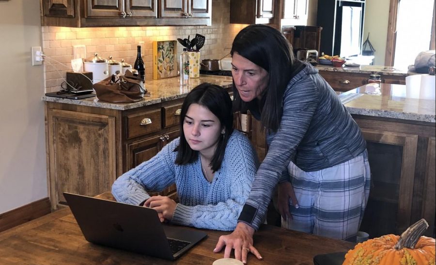 Mother, Lori Guilander, looks over her daughter Tessa’s shoulder while working on October 20. They are working together at their home in Carbondale. 