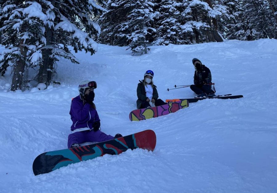 Carolyn Tanner, Gabi Echegaray, and Hannah Zack skiing and snowboarding at Snowmass Mountain while maintaining safety precautions. 