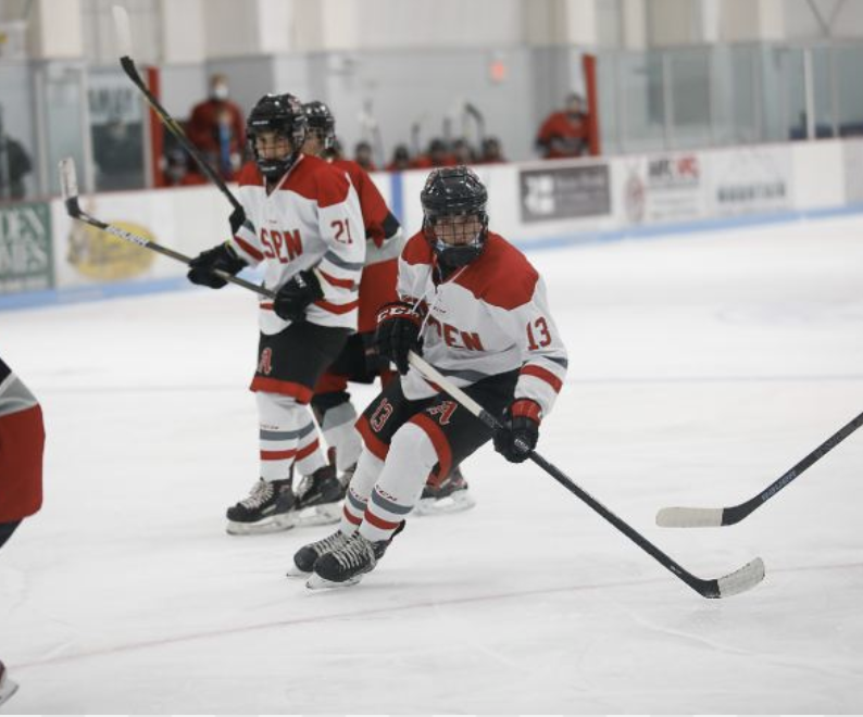 AHS boys hockey team skating towards goal during home game.