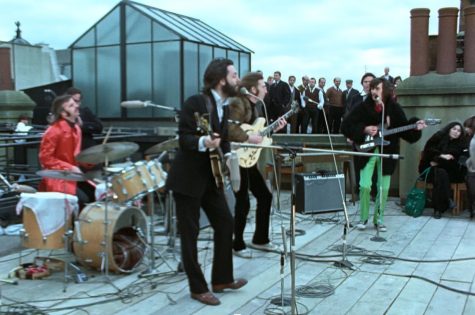 A screenshot from the docuseries showing Paul, John, George, and Ringo performing a rooftop concert on the Apple Corps building on January 30, 1969.