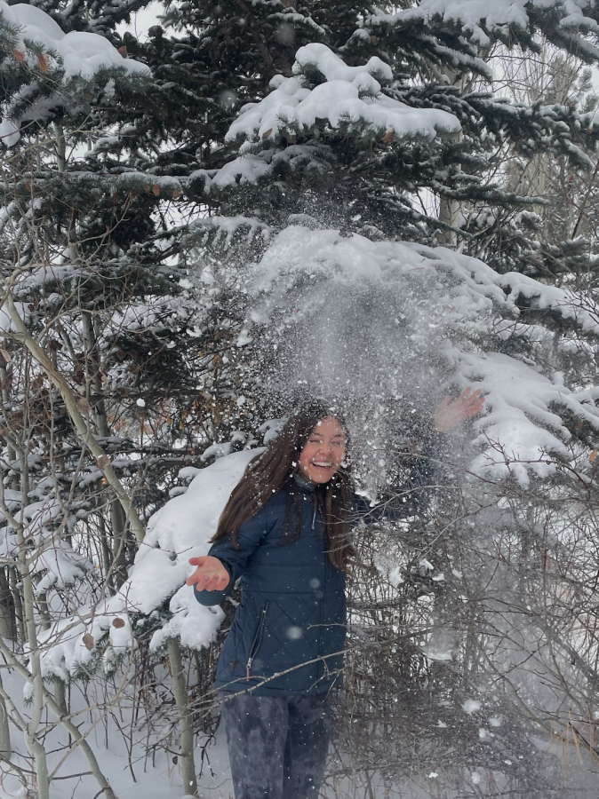 Elsa Tullar, Junior, enjoys the fresh, falling winter snow beneath a tree.