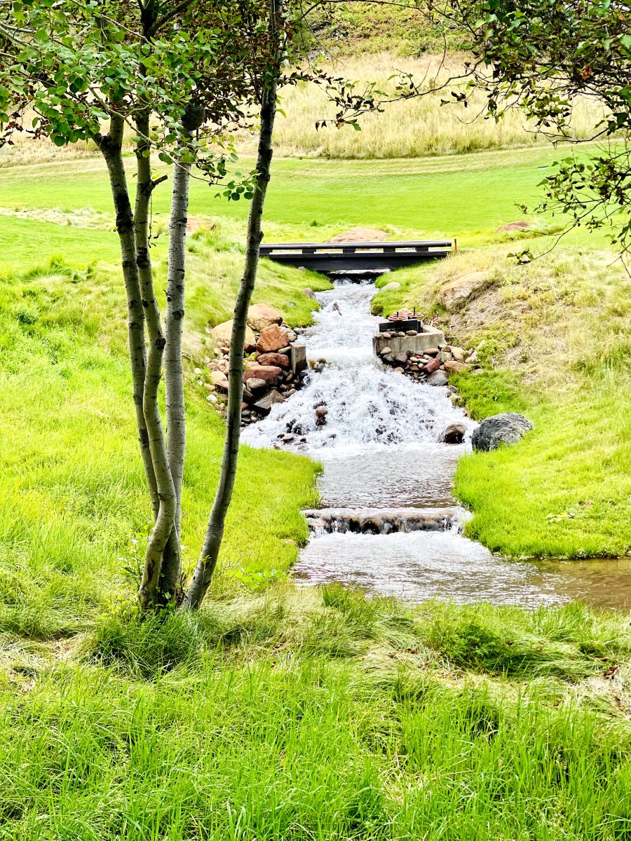 A stream runs under a bridge in the summer weather at Maroon Creek Golf Course.