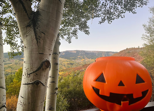 Jack-O-Lantern candy bucket sitting in front of the changing colors in Snowmass colorado, patiently awaiting the season for Trick-or-Treating. 