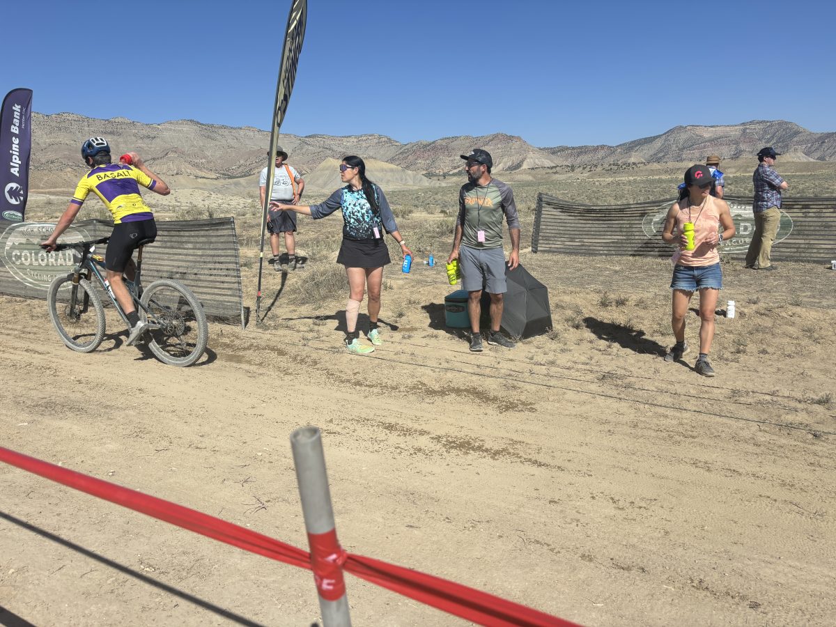 Kristen Heath hands a dunk bottle to her son, Liam, during his varsity race in Fruita. 