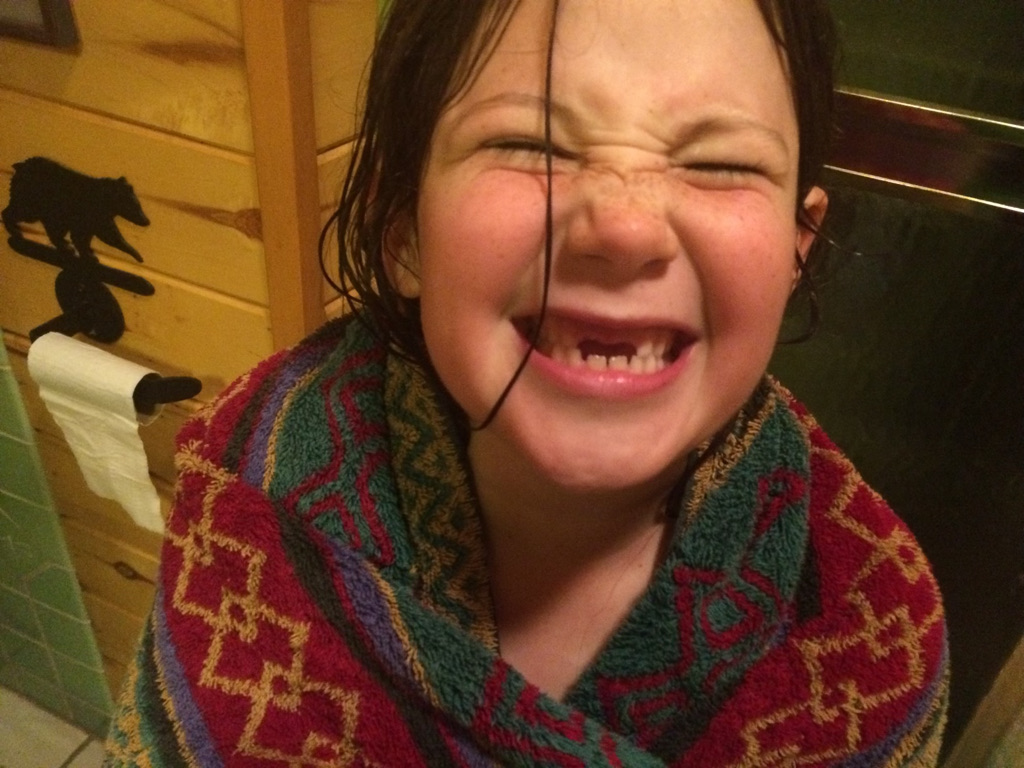 Young Quintessa Frisch wrapped in a towel, smiling at her mother, showing off her tooth-less smile.