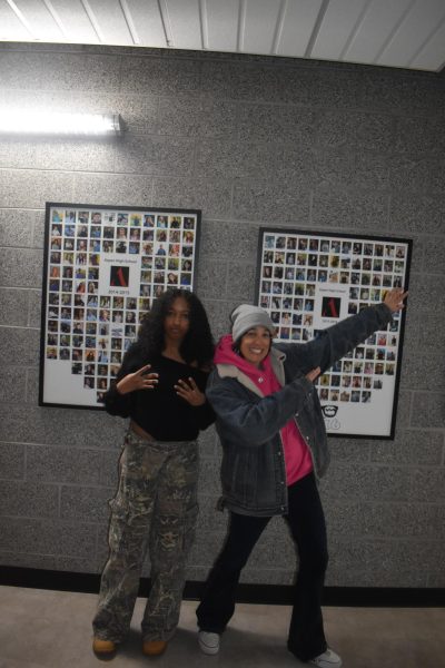 Gia Galindo Bartley and Sarah Ward pose in front of the 2014-2015 and 2015-2016 graduation pictures to represent trends in 2015 and 2025. 