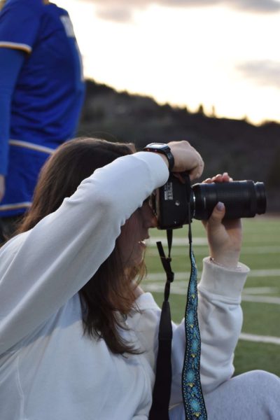 Sara Michelin focuses on her camera as she captures action at a boy's lacrosse game.