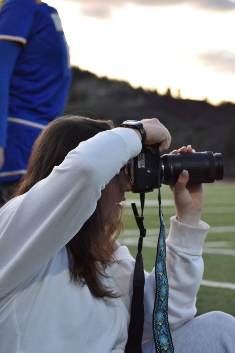 Sara Michelin focuses on her camera as she captures action at a boy's lacrosse game.