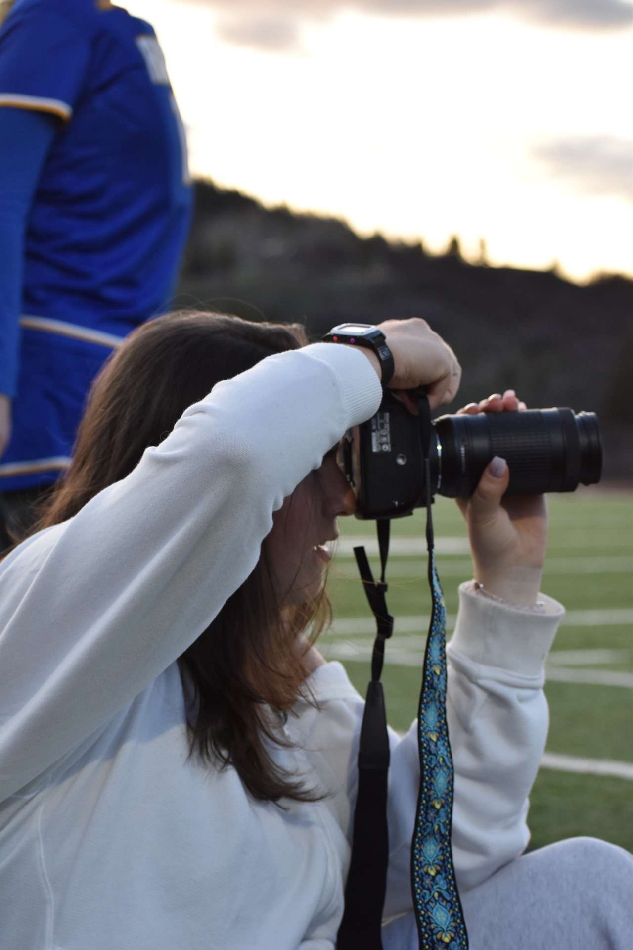 Sara Michelin focuses on her camera as she captures action at a boy's lacrosse game.