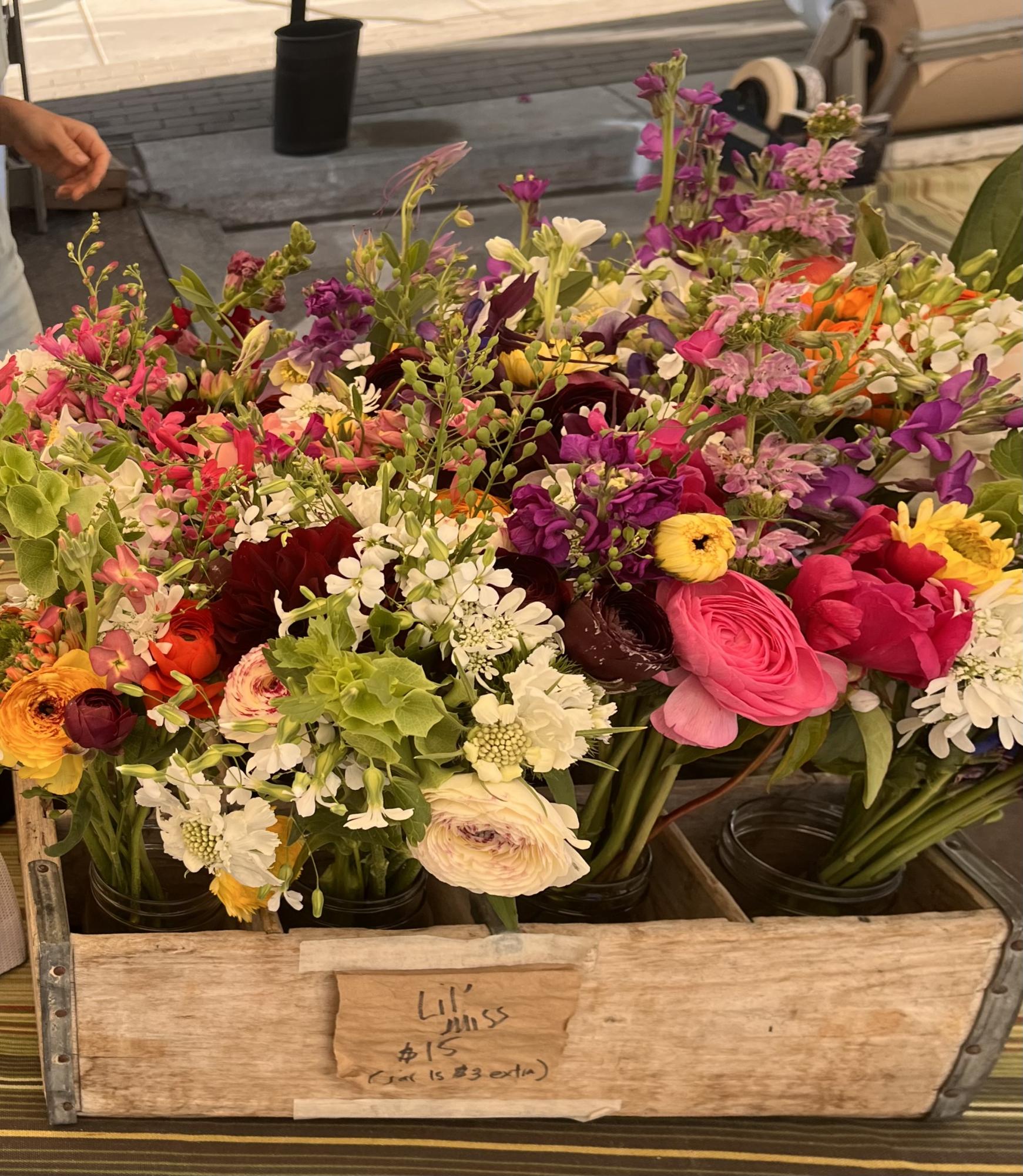 A box of various flowers is displayed in a booth at the Aspen Farmer's Market.